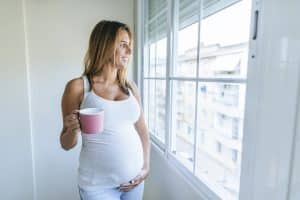 pregnant woman looking out of window holding mug 2022 03 08 01 25 30 utc